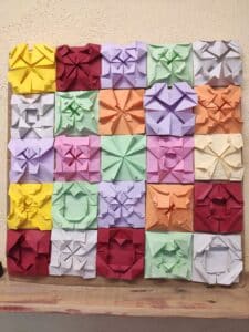 Mosaicos de papiroflexia de colores colocados sobre una mesa, una propuesta para explorar geometría, patrones y matemáticas de verano sin fichas.